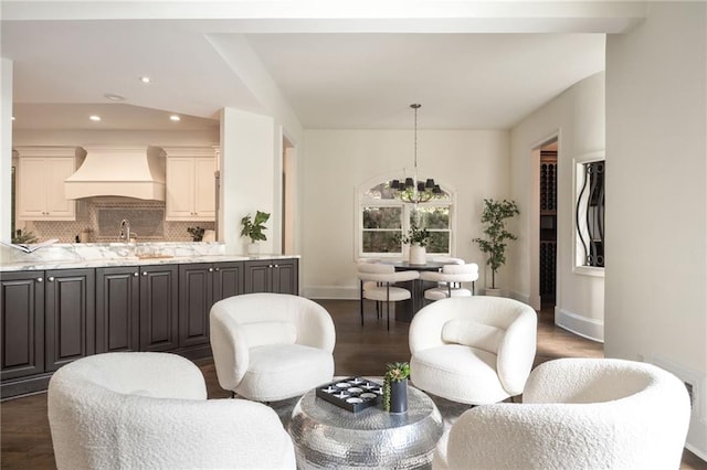 living room with dark hardwood / wood-style flooring, sink, and a notable chandelier