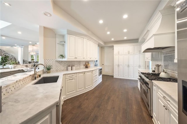 kitchen with high end stainless steel range oven, dark wood-type flooring, sink, white cabinets, and backsplash