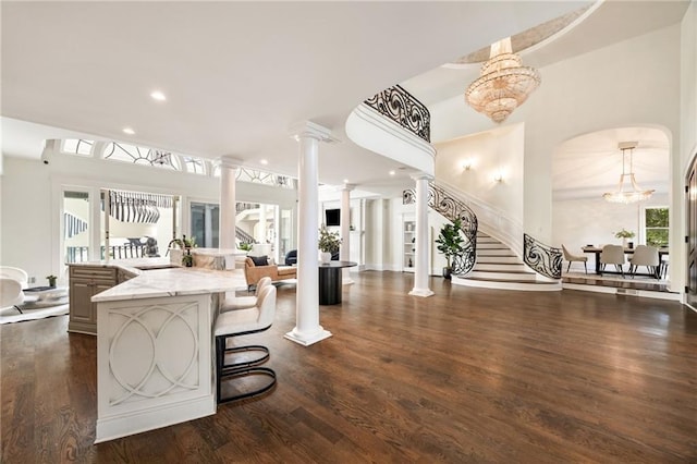 interior space featuring light stone counters, dark wood-type flooring, sink, a kitchen bar, and an inviting chandelier