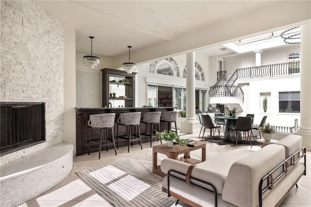 tiled living room with decorative columns and a chandelier