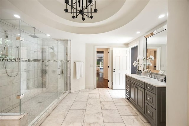 bathroom with vanity, a raised ceiling, a shower with shower door, and a notable chandelier