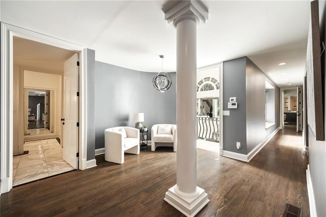 living area featuring an inviting chandelier, dark hardwood / wood-style floors, and ornate columns