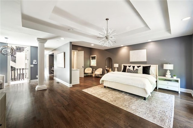 bedroom with a tray ceiling, dark hardwood / wood-style flooring, and a chandelier