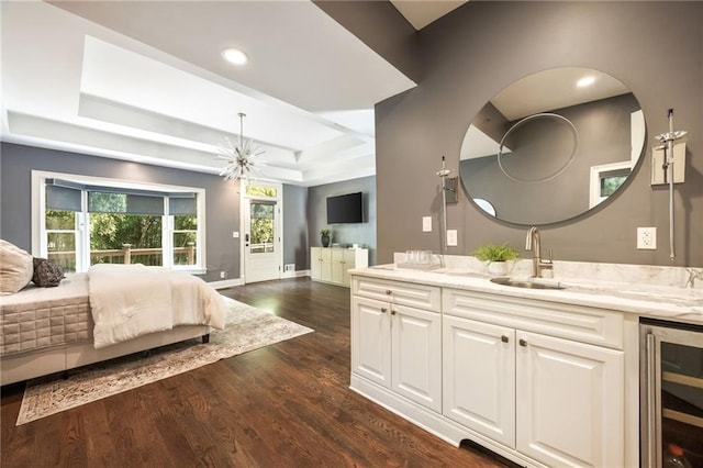 bedroom featuring a raised ceiling, sink, beverage cooler, dark wood-type flooring, and a chandelier