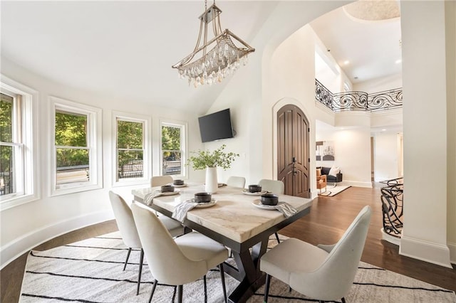 dining area with a high ceiling, an inviting chandelier, and dark wood-type flooring