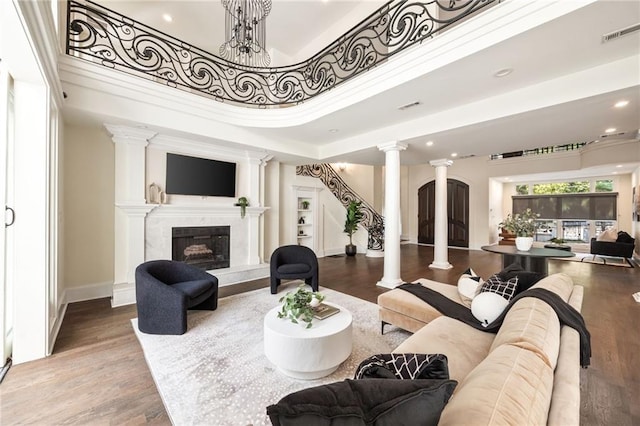 living room featuring wood-type flooring, a towering ceiling, and ornate columns