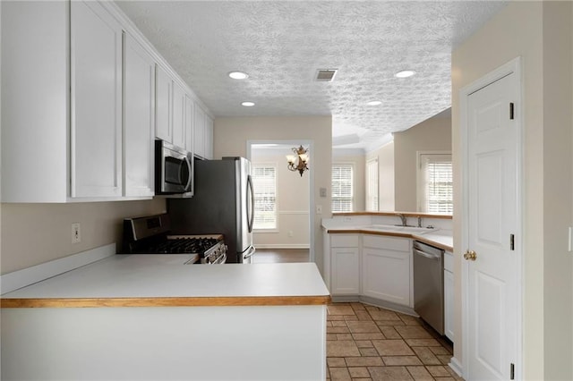 16 Kentucky Walk NE, Cartersville, GA 30121 - kitchen with stainless steel appliances, a peninsula, white cabinets, light countertops, and recessed lighting
