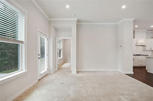 unfurnished living room featuring a healthy amount of sunlight, baseboards, and crown molding