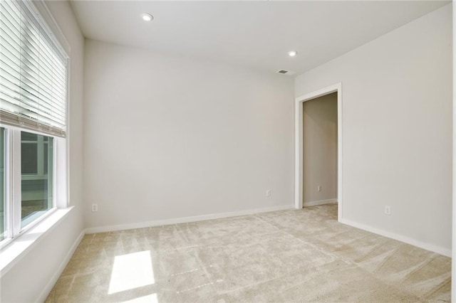 empty room featuring recessed lighting, light colored carpet, and baseboards