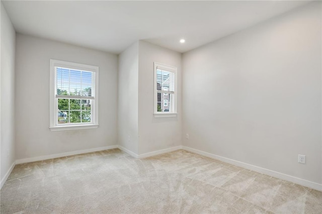 empty room with a healthy amount of sunlight, recessed lighting, baseboards, and light colored carpet