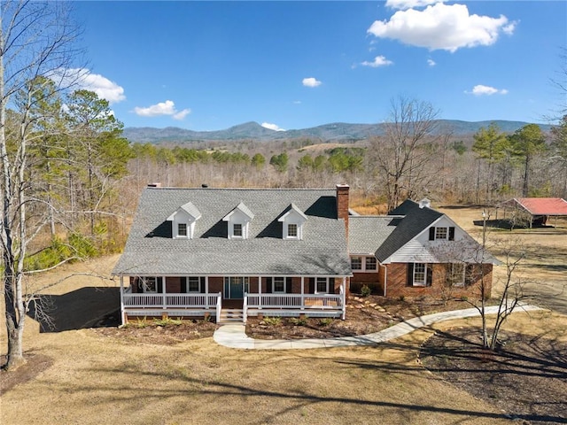 view of front of house with a mountain view, covered porch, and a front yard