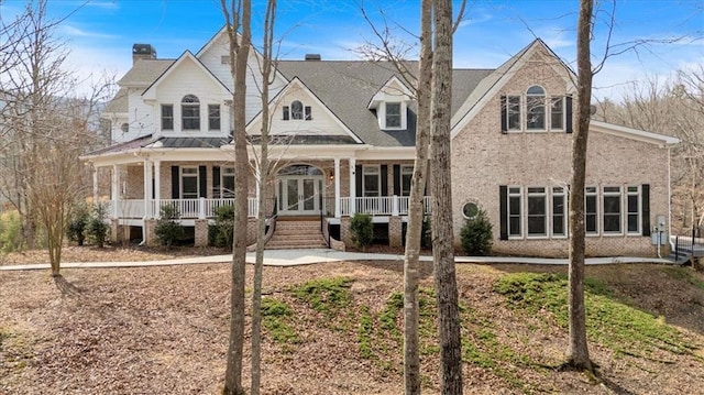 view of front of house featuring brick siding, covered porch, french doors, and a chimney