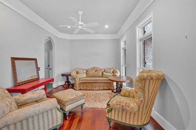 living room with arched walkways, crown molding, baseboards, and wood finished floors