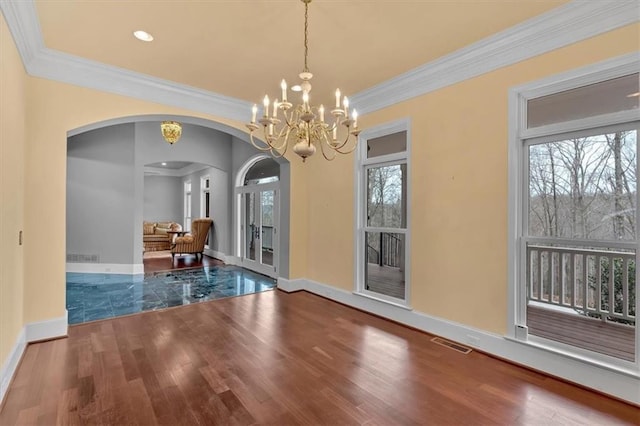 unfurnished dining area with arched walkways, visible vents, an inviting chandelier, and wood finished floors