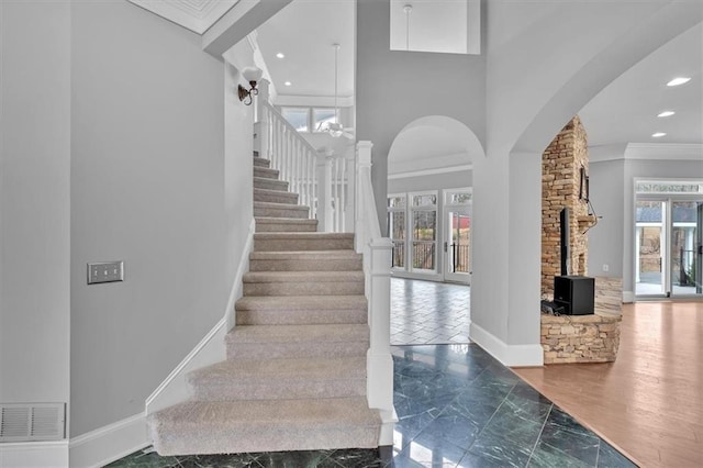 staircase featuring crown molding, a healthy amount of sunlight, baseboards, and visible vents