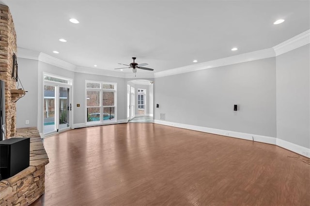 unfurnished living room featuring baseboards, a stone fireplace, wood finished floors, and a ceiling fan