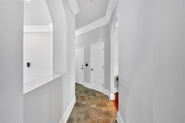 corridor with baseboards, arched walkways, crown molding, and stone finish floor