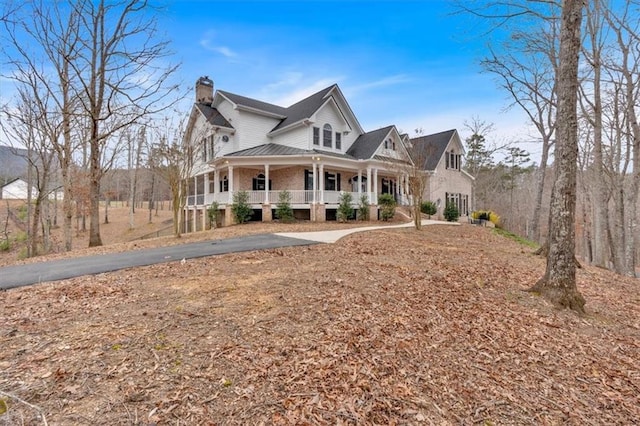 view of front of house featuring metal roof, covered porch, and a chimney