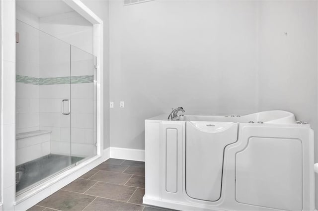 bathroom featuring baseboards, a garden tub, a stall shower, and tile patterned flooring