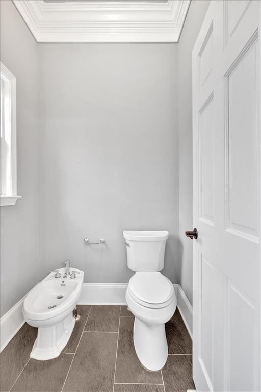 half bath with toilet, baseboards, and ornamental molding