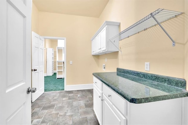 clothes washing area featuring stone finish flooring, baseboards, and washer hookup