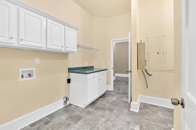 clothes washing area featuring baseboards, cabinet space, hookup for a washing machine, and stone finish floor