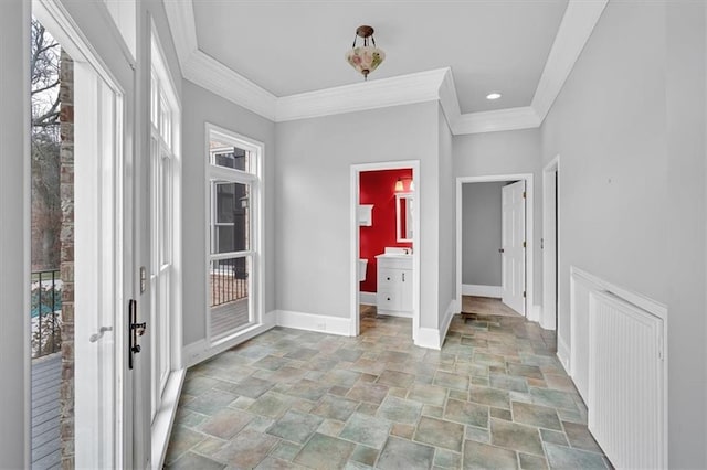 foyer entrance featuring a wealth of natural light, stone finish floor, crown molding, and baseboards