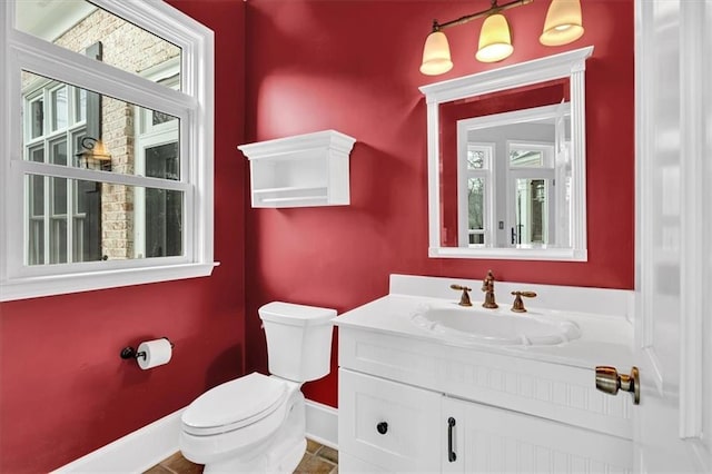 bathroom featuring baseboards, toilet, and vanity