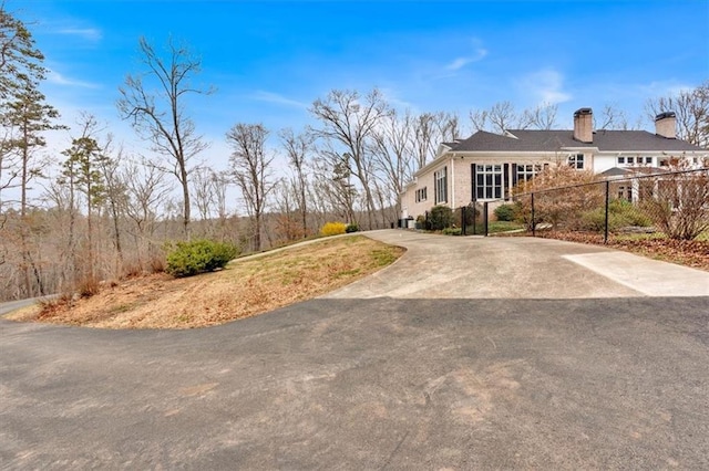 exterior space with concrete driveway, fence, and a chimney