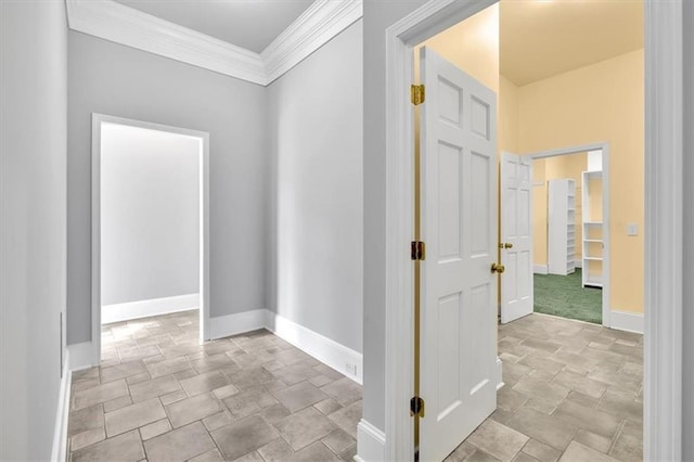 hall featuring stone finish flooring, crown molding, and baseboards