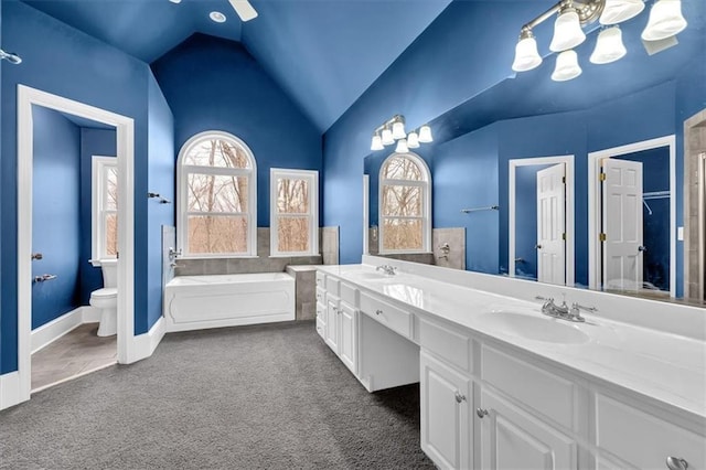 bathroom with lofted ceiling, double vanity, a sink, a garden tub, and toilet