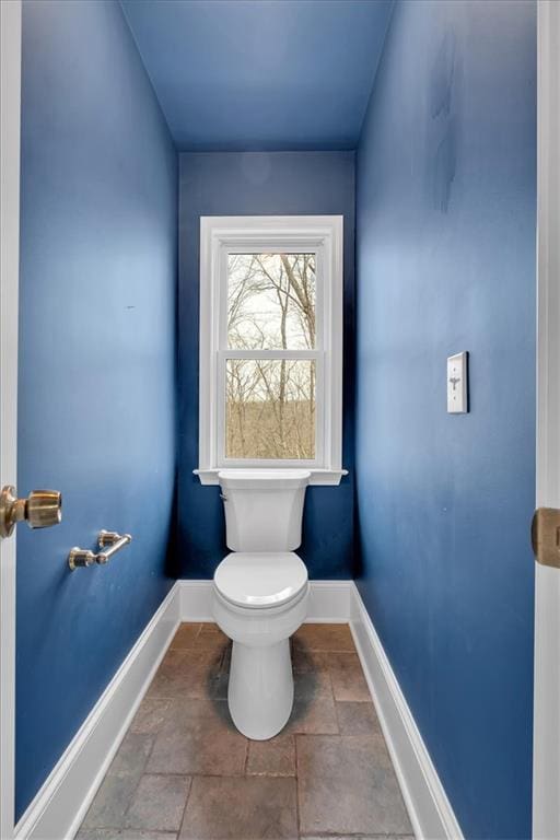 bathroom featuring stone finish floor, toilet, and baseboards