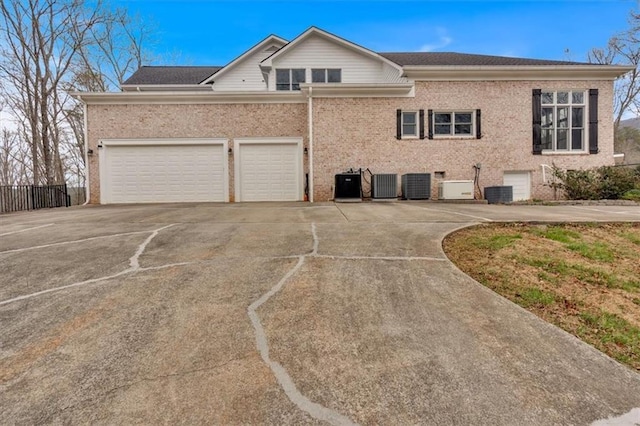 exterior space with central AC, fence, brick siding, and driveway