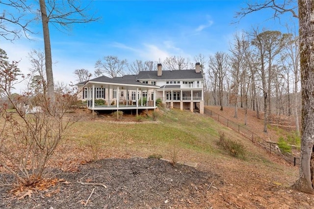 back of property featuring a wooden deck, a lawn, a chimney, and fence