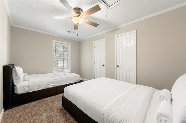 bedroom featuring carpet floors, ornamental molding, a ceiling fan, attic access, and a textured ceiling
