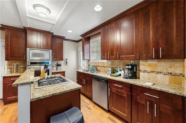 kitchen featuring stainless steel appliances, a sink, light wood-style floors, crown molding, and backsplash