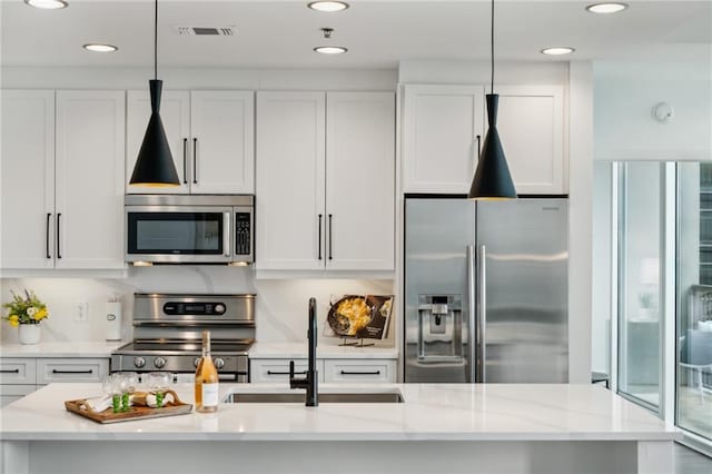 kitchen with visible vents, light stone countertops, stainless steel appliances, white cabinetry, and a sink