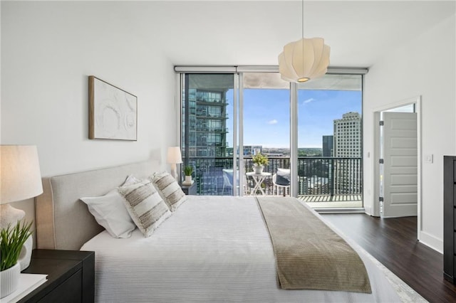 bedroom featuring a city view, wood finished floors, floor to ceiling windows, baseboards, and access to exterior