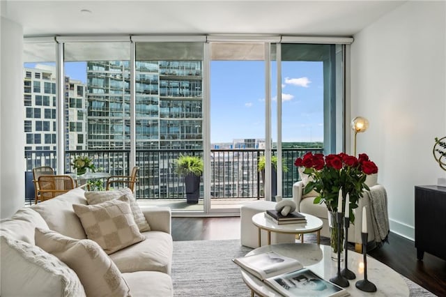 living room with a view of city, wood finished floors, baseboards, and expansive windows