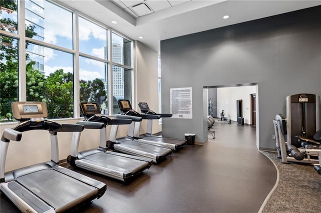 exercise room with recessed lighting, baseboards, and a towering ceiling