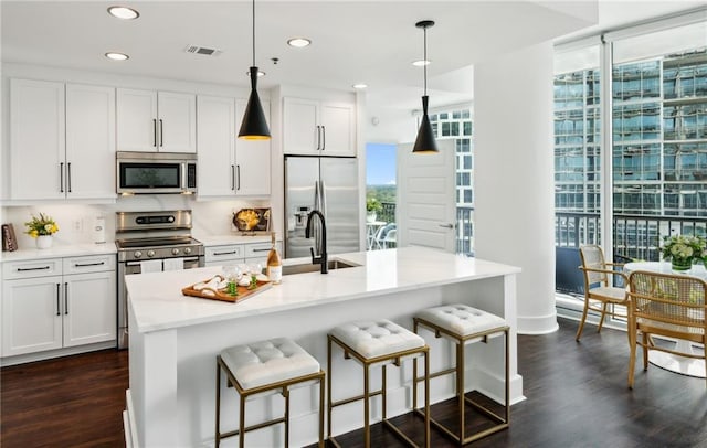 kitchen featuring decorative light fixtures, a healthy amount of sunlight, appliances with stainless steel finishes, and dark wood-style flooring