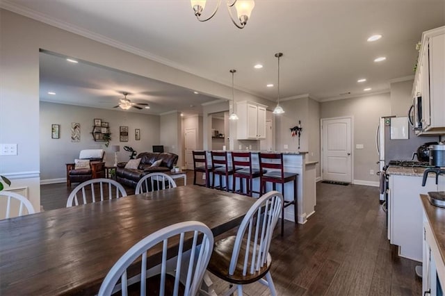 dining area featuring ceiling fan with notable chandelier, ornamental molding, and dark hardwood / wood-style flooring