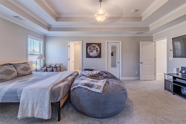 carpeted bedroom with ornamental molding and a tray ceiling