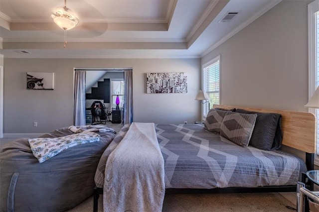 carpeted bedroom with a tray ceiling and crown molding