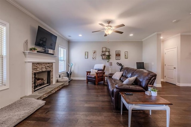 living room with ceiling fan, a stone fireplace, dark hardwood / wood-style floors, and crown molding