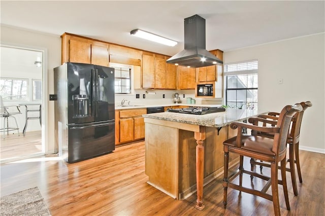 kitchen with light hardwood / wood-style floors, island range hood, kitchen peninsula, black appliances, and sink