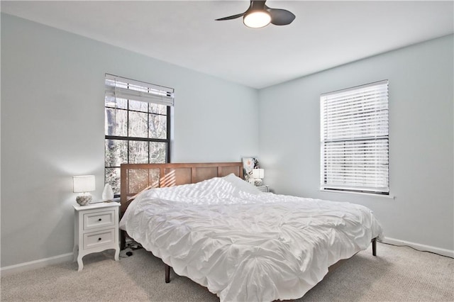 bedroom with ceiling fan, light colored carpet, and multiple windows