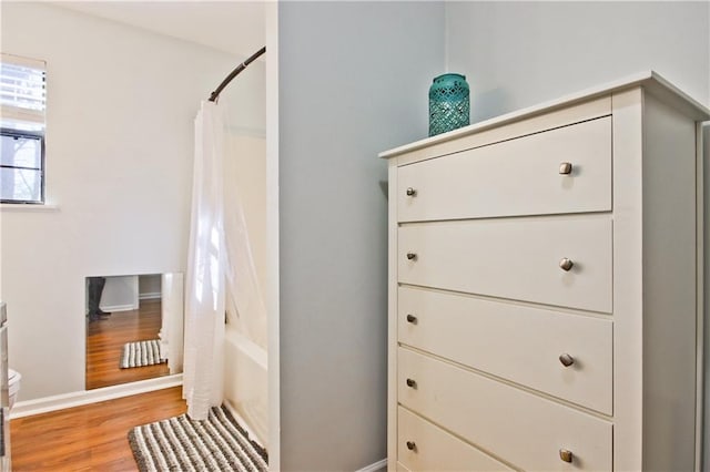 bathroom featuring toilet, shower / bath combination with curtain, and hardwood / wood-style flooring