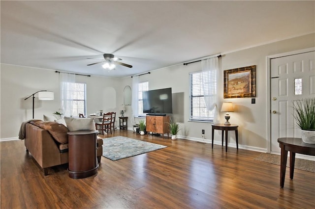 living room with dark wood-type flooring, ceiling fan, and a wealth of natural light