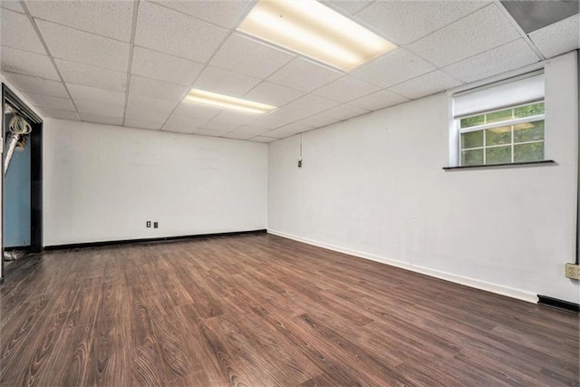 unfurnished room with dark hardwood / wood-style flooring and a drop ceiling